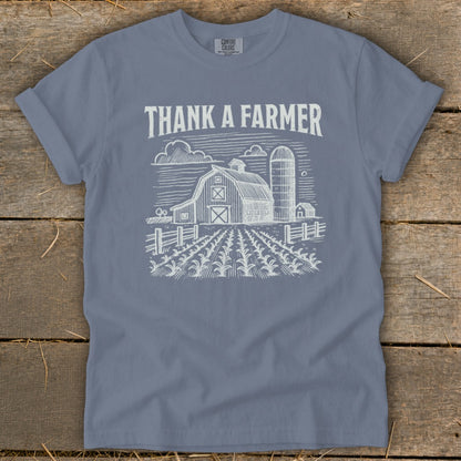 Blue t-shirt with "THANK A FARMER" text and a barn illustration.