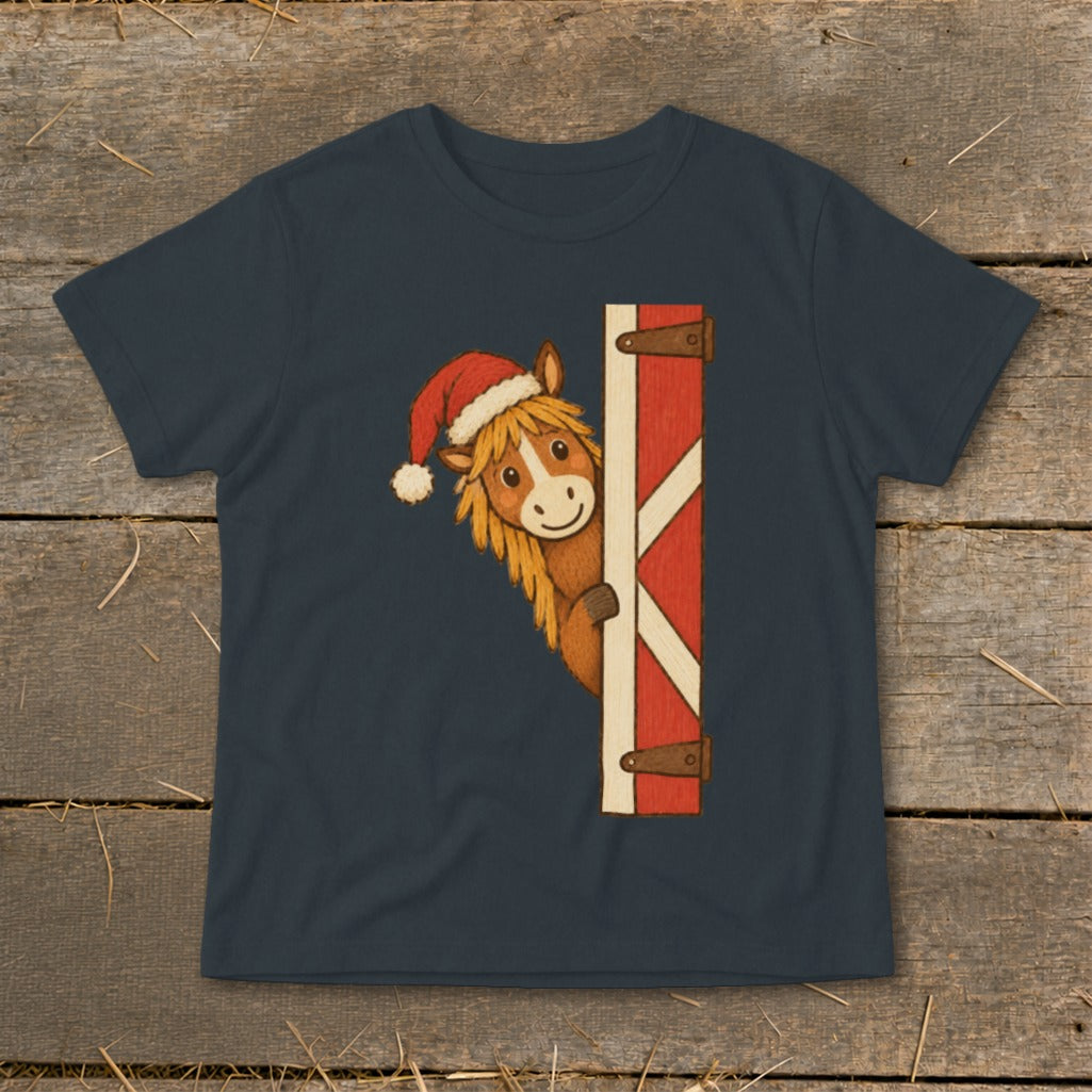Christmas horse wearing a Santa hat peeks from behind a barn door.