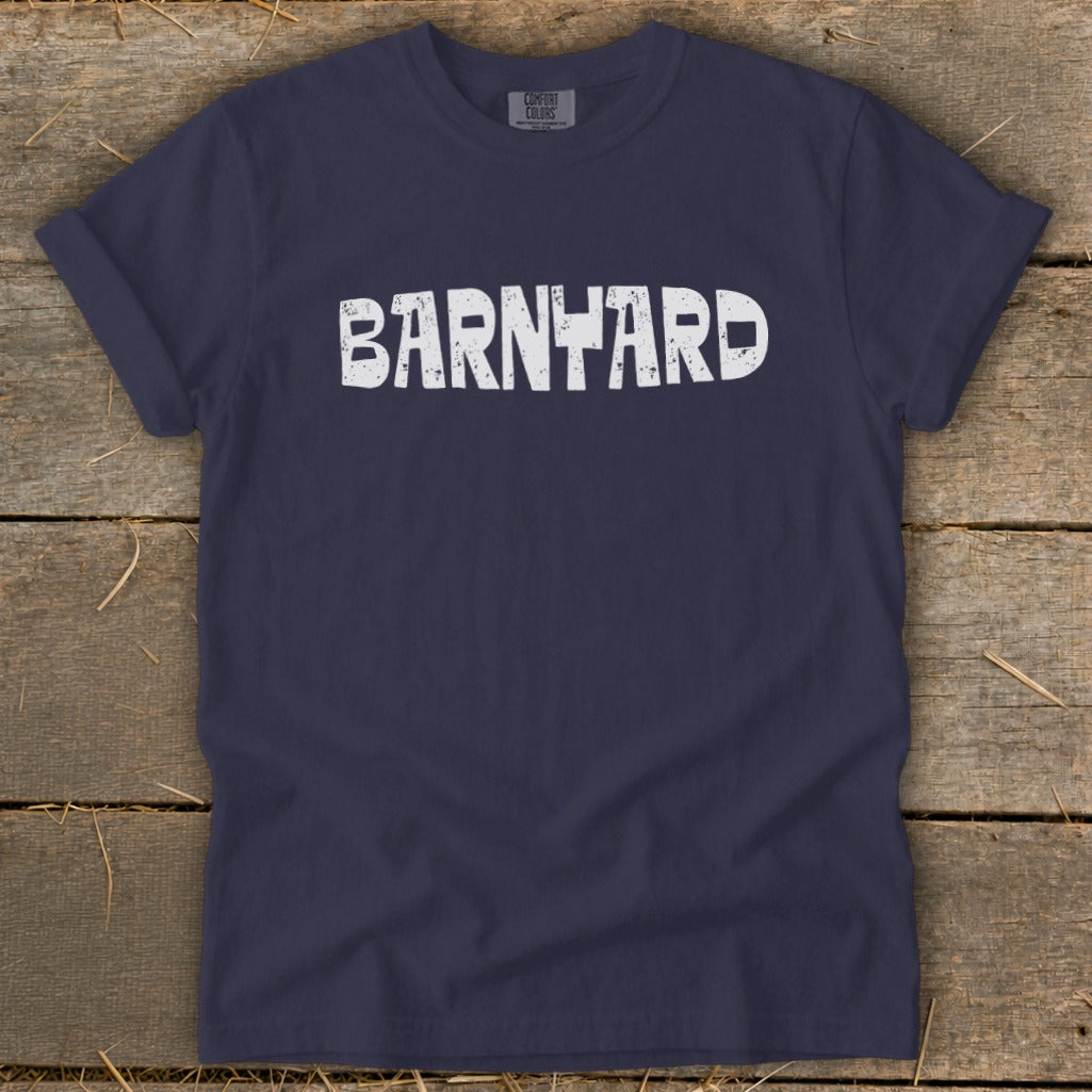 Navy blue short-sleeve t-shirt with distressed white text reading BARNYARD laid flat on wood planks.