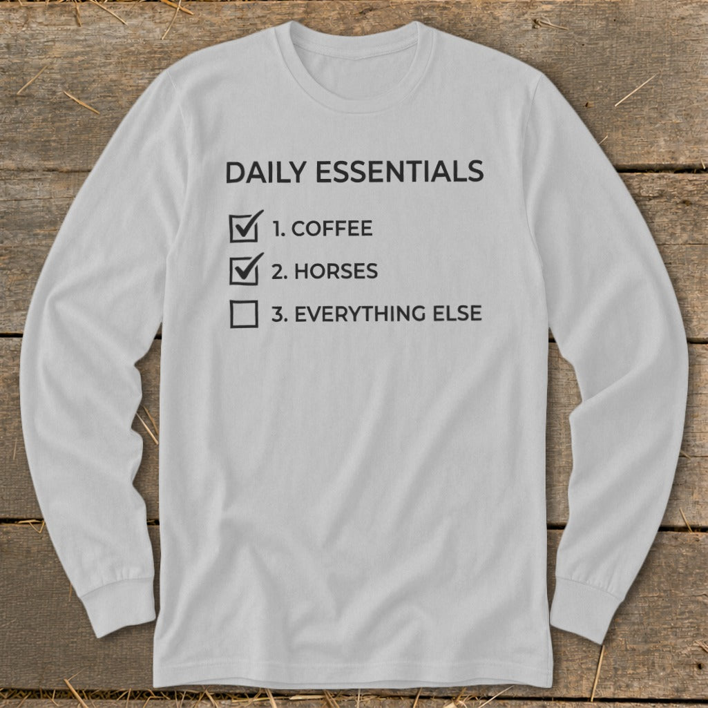 Long-sleeve shirt with "Daily Essentials" checklist: 1. Coffee, 2. Horses, 3. Everything else.
