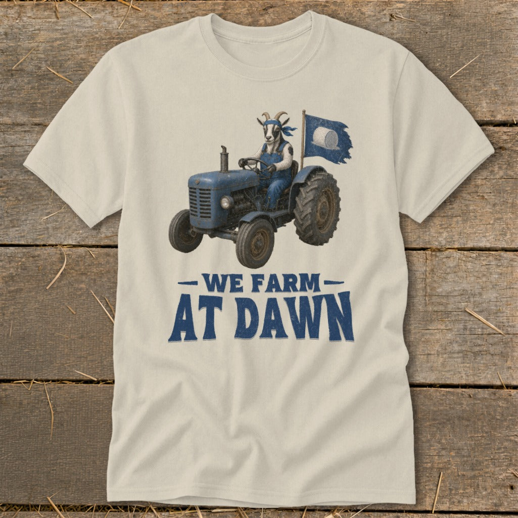 T-shirt with a goat driving a blue tractor, flying a flag, with text "We Farm At Dawn".