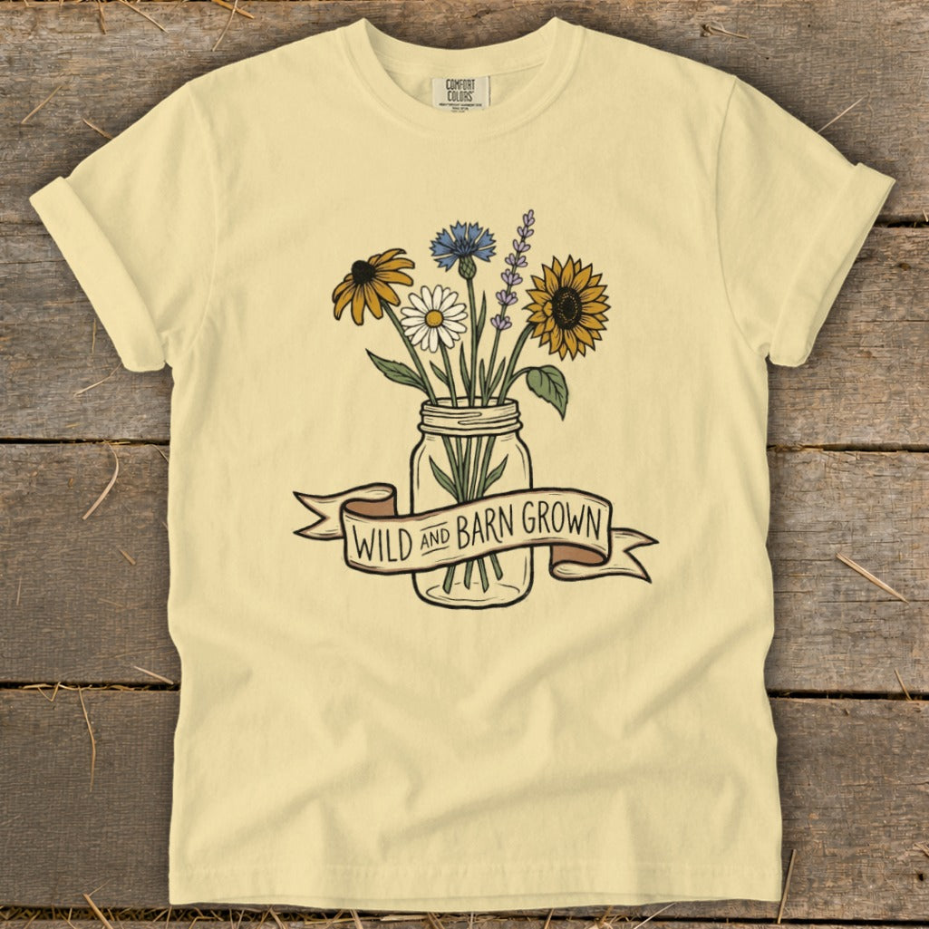 Pale yellow t-shirt with a mason jar of wildflowers and the text "WILD AND BARN GROWN".