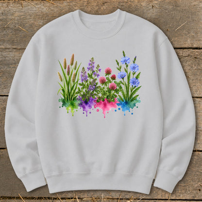 A light gray crewneck sweatshirt featuring a watercolor graphic of wildflowers over color-splashed bases.