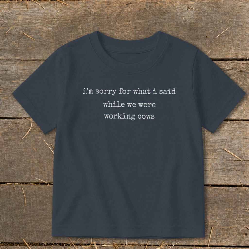 Navy t-shirt with white text that says "i'm sorry for what i said while we were working cows".