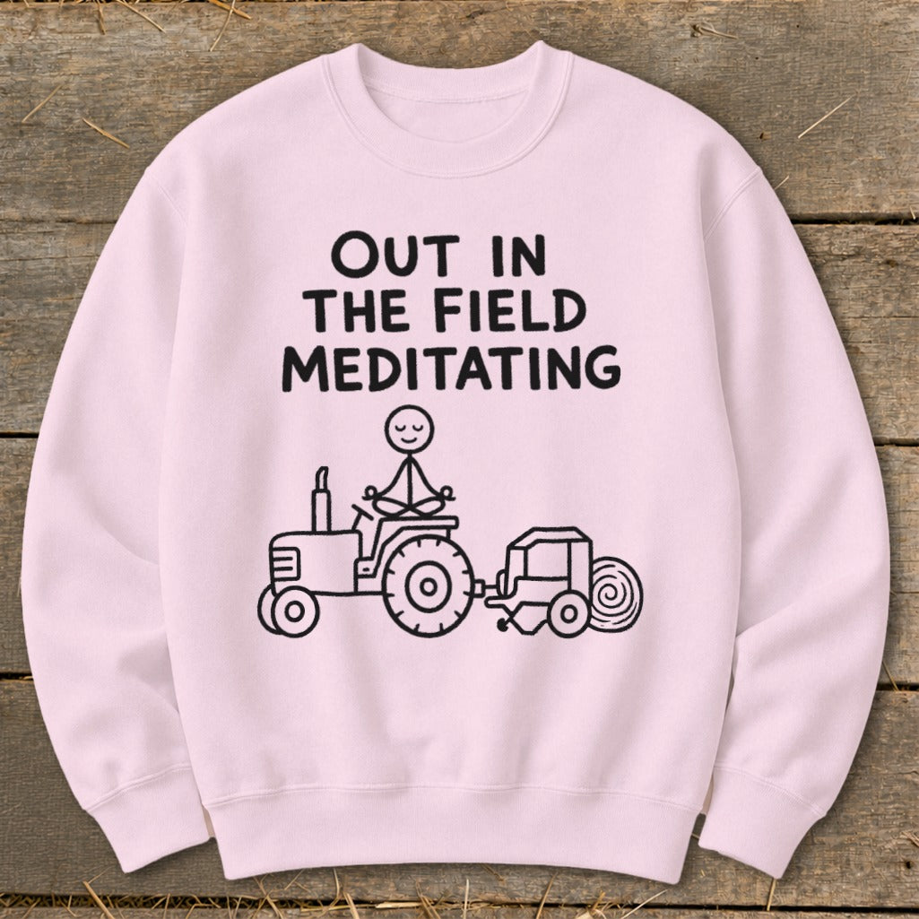 Pink sweatshirt with black graphic of stick figure meditating on tractor with baler.