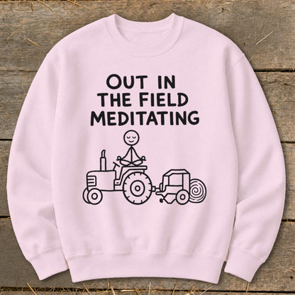 Pink sweatshirt with black graphic of stick figure meditating on tractor with baler.