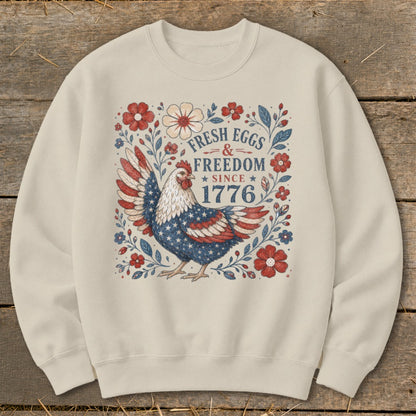 Cream sweatshirt with a patriotic chicken and floral graphic that reads "Fresh Eggs & Freedom Since 1776".
