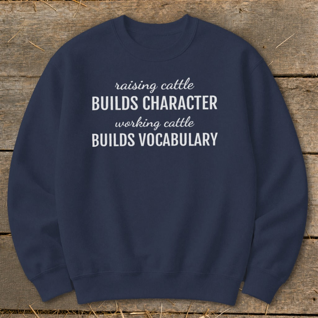 Navy sweatshirt with white text "raising cattle BUILDS CHARACTER working cattle BUILDS VOCABULARY".