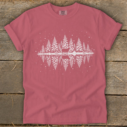 Pink t-shirt with white pine trees and a guitar reflected in water.