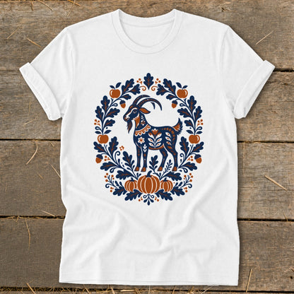 White short-sleeve t-shirt featuring a folk art illustration of a goat surrounded by leaves, acorns, and pumpkins.