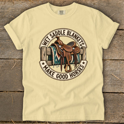 T-shirt with a western saddle on a fence, featuring text "Wet Saddle Blankets Make Good Horses".