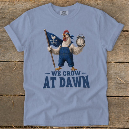 A chicken in overalls holds a flag and alarm clock, with text "We Grow At Dawn."