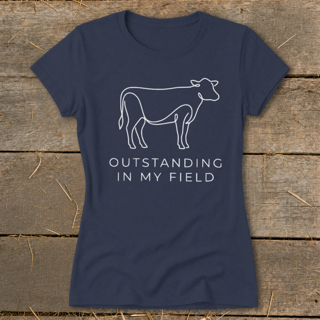 Navy t-shirt with white cow outline and text "OUTSTANDING IN MY FIELD."
