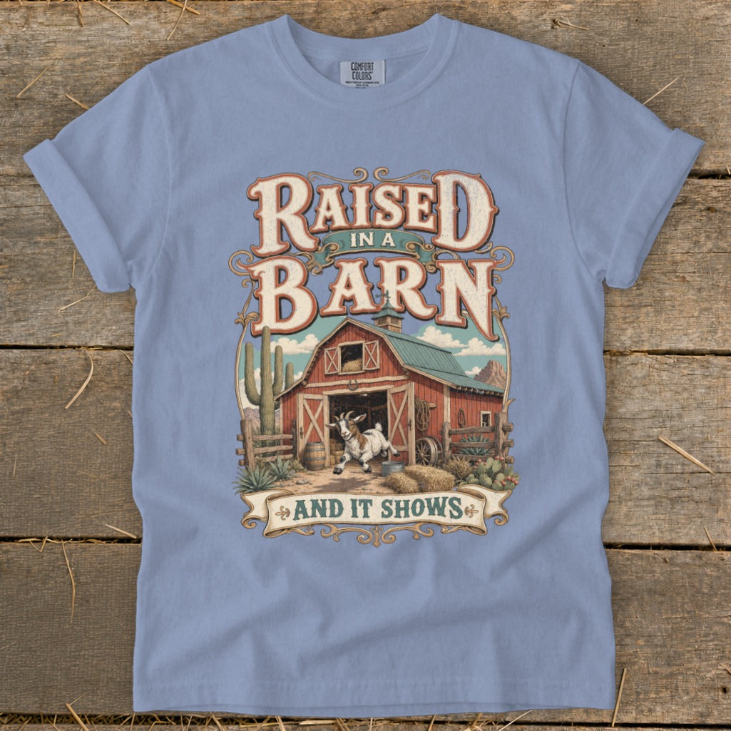 T-shirt design with text "Raised in a Barn and It Shows" and a goat in front of a barn.