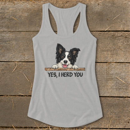 Grey tank top with a smiling border collie peeking over a wooden bar, text says "YES, I HERD YOU."