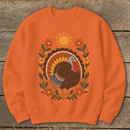 Orange sweatshirt with a stylized turkey and floral design for Thanksgiving.