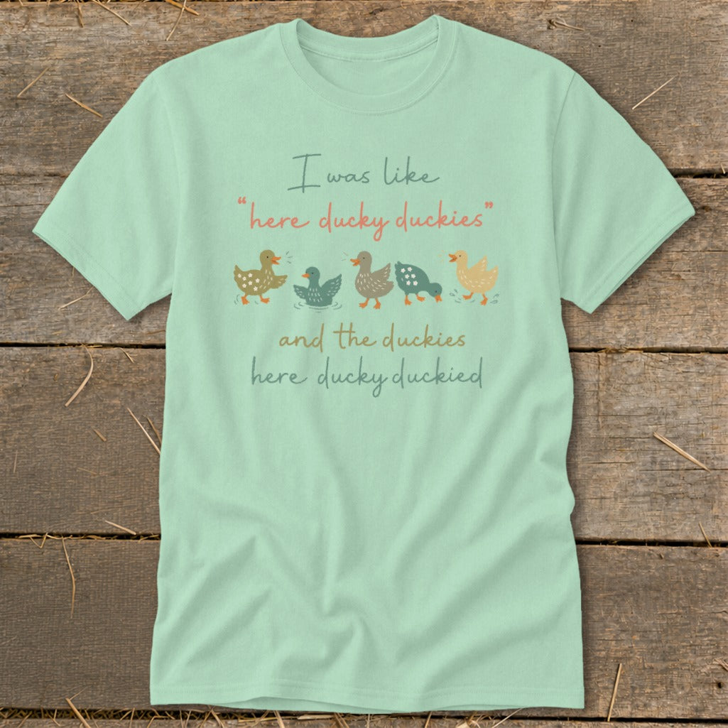 Light blue t-shirt with cartoon ducks and text "I was like 'here ducky duckies' and the duckies here ducky duckied."