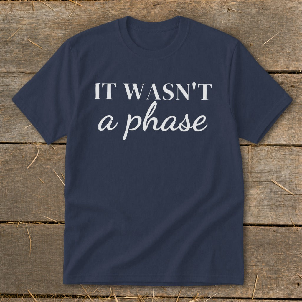 Navy t-shirt with white text "IT WASN'T a phase" on rustic wooden background.