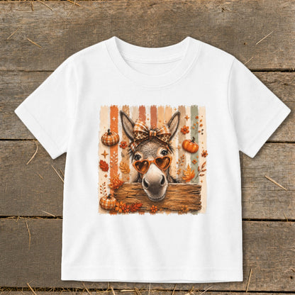 Donkey with heart sunglasses and bow peeking over wooden sign with pumpkins and leaves.