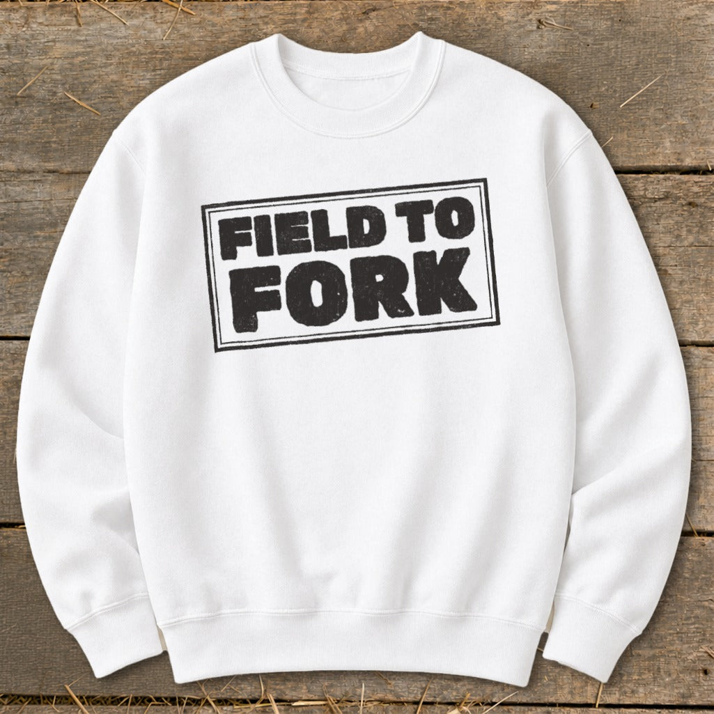 A white crewneck sweatshirt featuring a black boxed graphic with the text "FIELD TO FORK" centered on the chest.