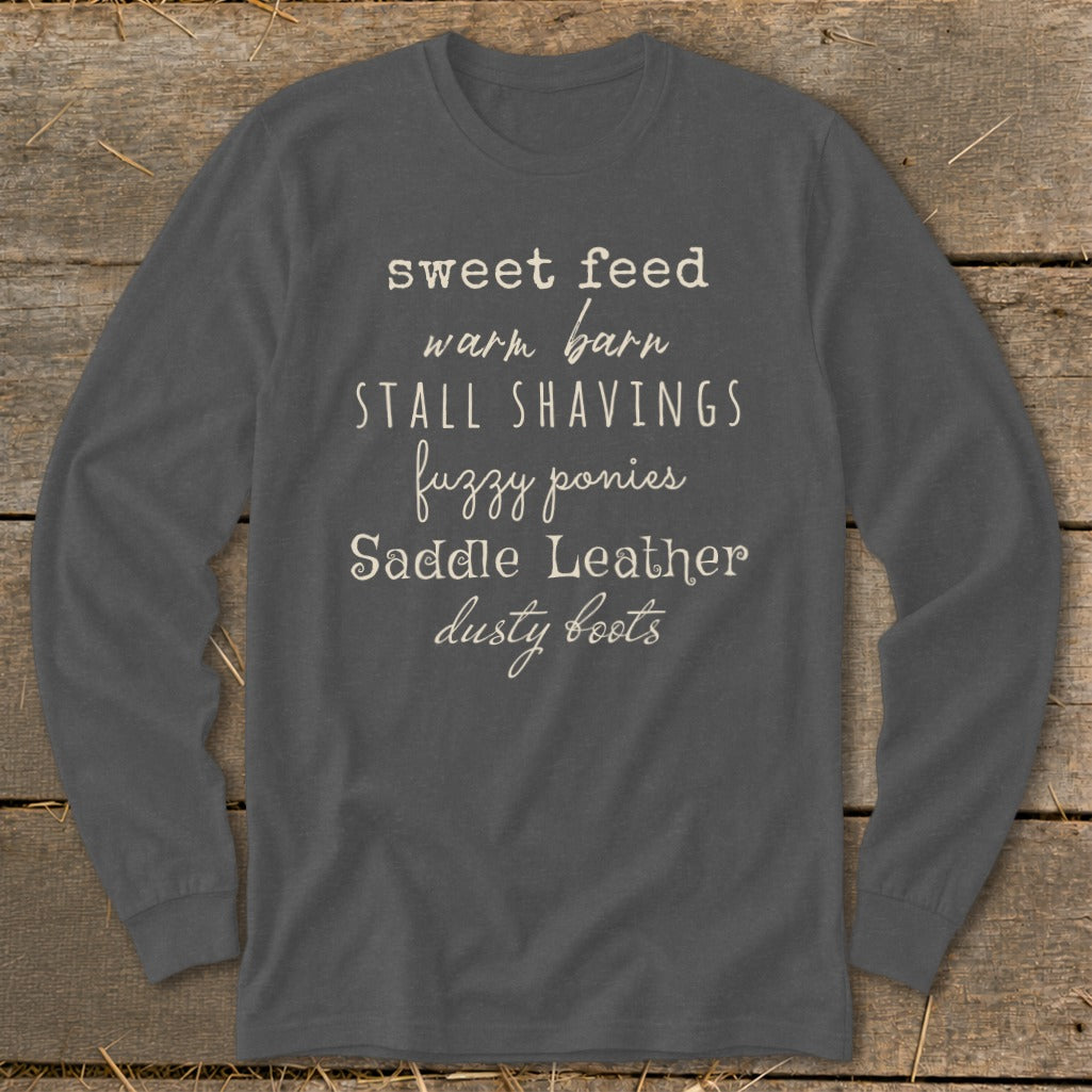 Dark grey long-sleeve shirt with "sweet feed warm barn STALL SHAVINGS fuzzy ponies Saddle Leather dusty boots" text.
