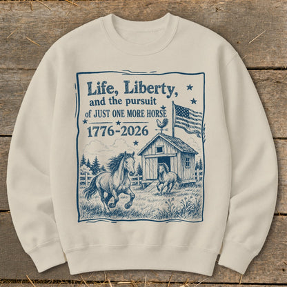 Cream sweatshirt with "Life, Liberty, and the pursuit of JUST ONE MORE HORSE 1776-2026" text and horses.