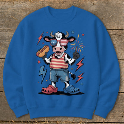Cartoon cow wearing American flag sunglasses, holding a hot dog and sparkler.