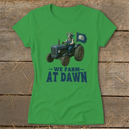 Green t-shirt with illustration of goat driving tractor with flag, text "WE FARM AT DAWN".