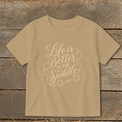 Tan t-shirt with "Life is Better in the Saddle" text and horse bit graphic.