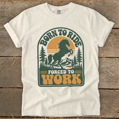 T-shirt with graphic of a rearing horse, mountains, trees, and text "Born to Ride Forced to Work".