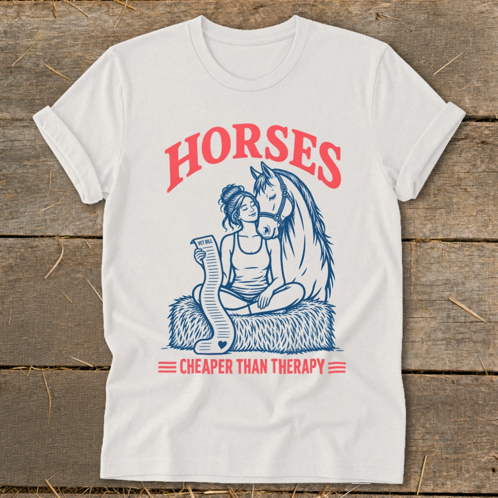 White t-shirt with a blue and pink graphic of a woman holding a vet bill beside a horse.