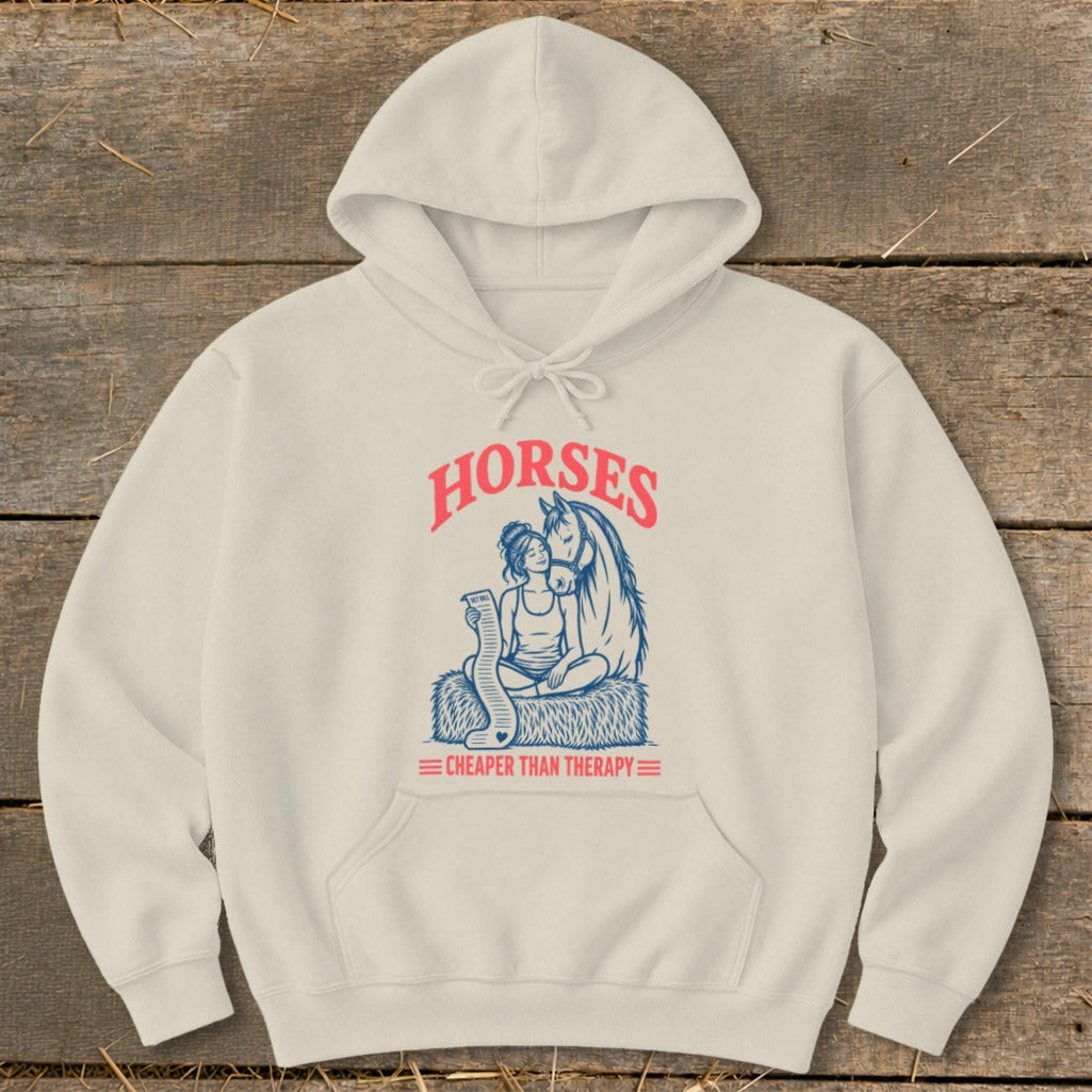 Cream hoodie with graphic "HORSES CHEAPER THAN THERAPY" and horse and person illustration.
