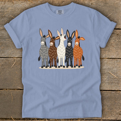 A periwinkle t-shirt featuring an illustration of five colorful donkeys standing together on a rustic wooden background.