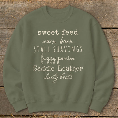 Olive sweatshirt with text: sweet feed, warm barn, stall shavings, fuzzy ponies, saddle leather, dusty boots.