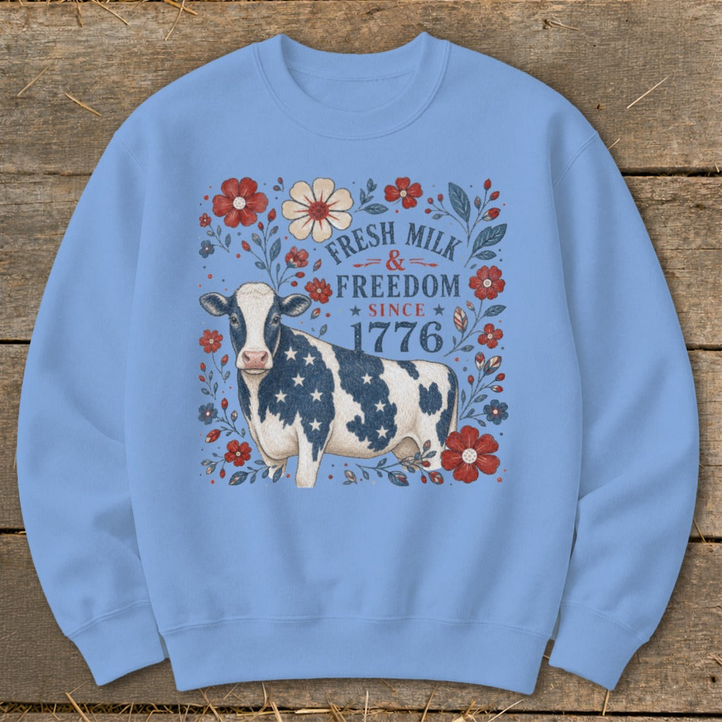 Light blue sweatshirt with a cow and floral design that reads "Fresh Milk & Freedom Since 1776".