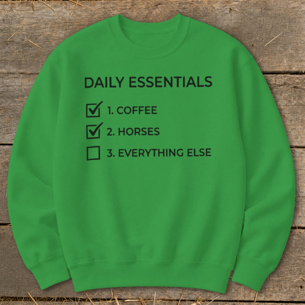 Green sweatshirt with "Daily Essentials" checklist: coffee, horses, everything else.