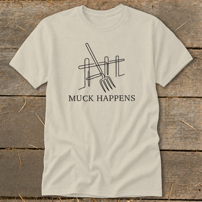 Beige t-shirt with line art of a pitchfork leaning against a fence and the text "MUCK HAPPENS".