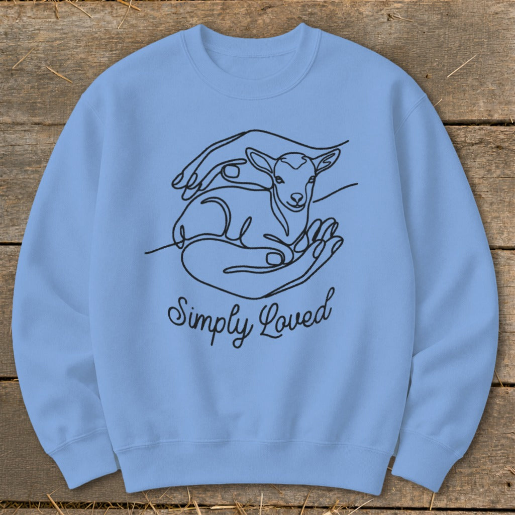 Light blue sweatshirt with black line art of hands holding a lamb and the text "Simply Loved".