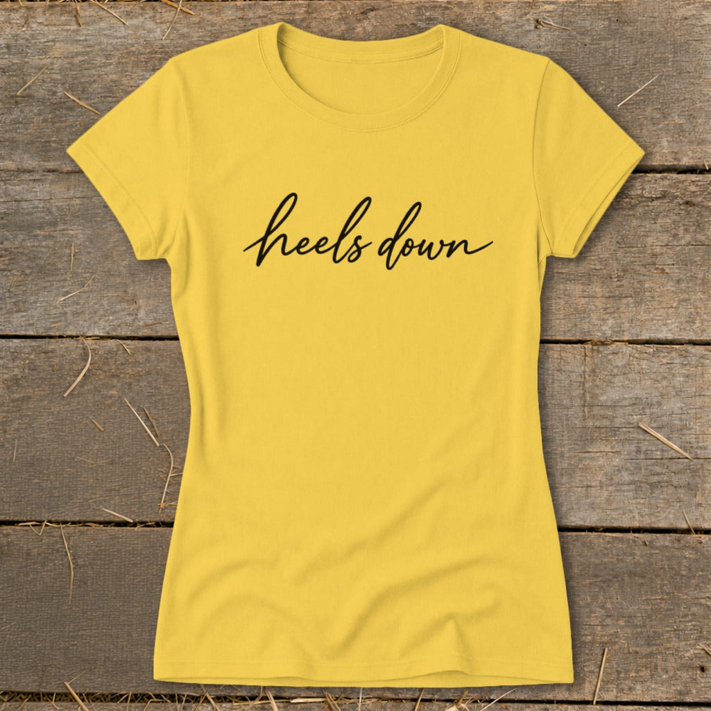 Yellow t-shirt with black cursive text "heels down".