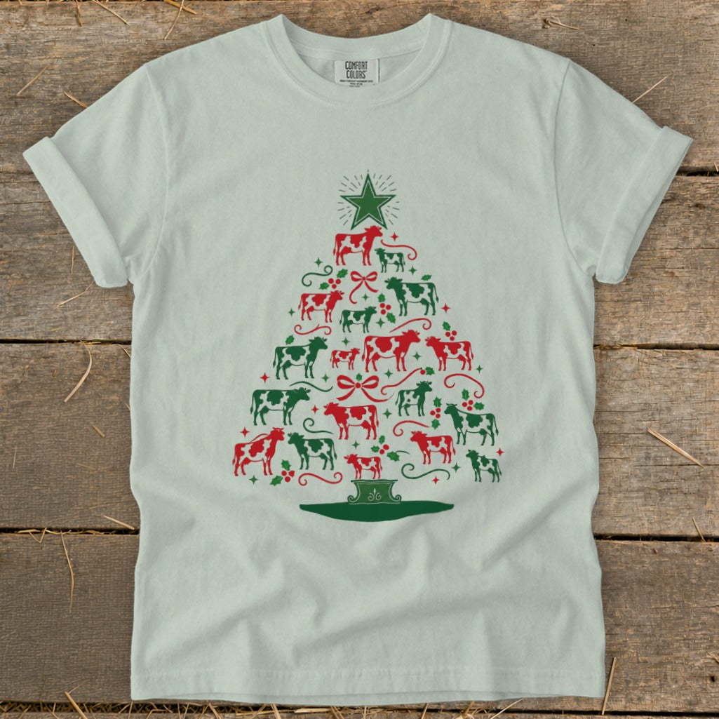White t-shirt with a Christmas tree made of red and green cows and holly.