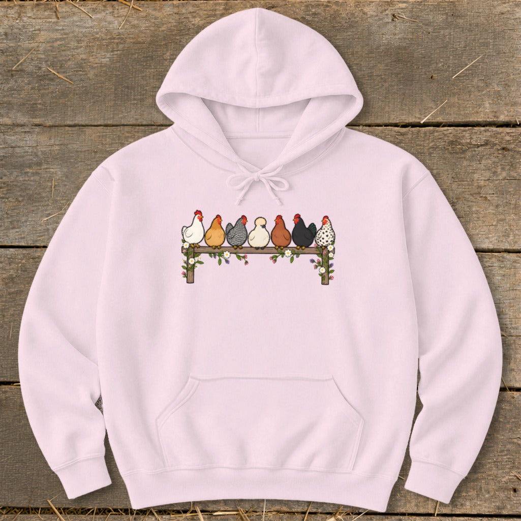 Light pink hoodie featuring a graphic of seven colorful chickens perched on a flower-covered fence.