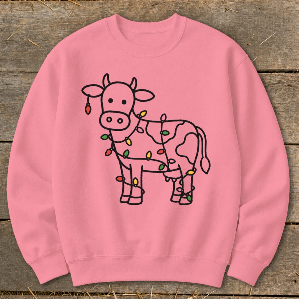 Pink crewneck sweatshirt with a black outline drawing of a cow wrapped in colorful holiday lights.