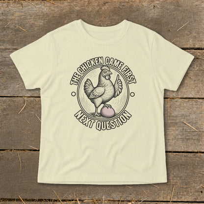 Cream t-shirt with "The chicken came first. Next question" graphic.