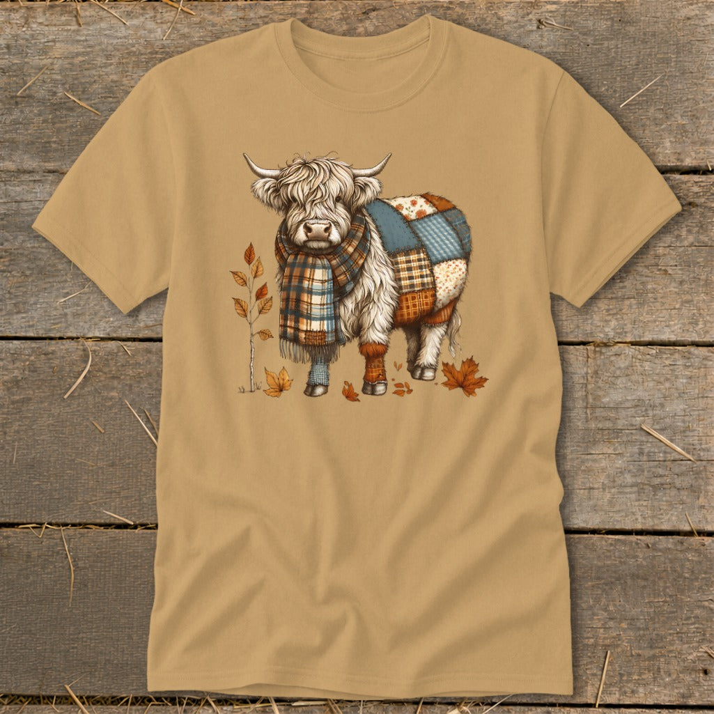 Fluffy Highland cow wearing a plaid scarf and patchwork blanket, with autumn leaves.
