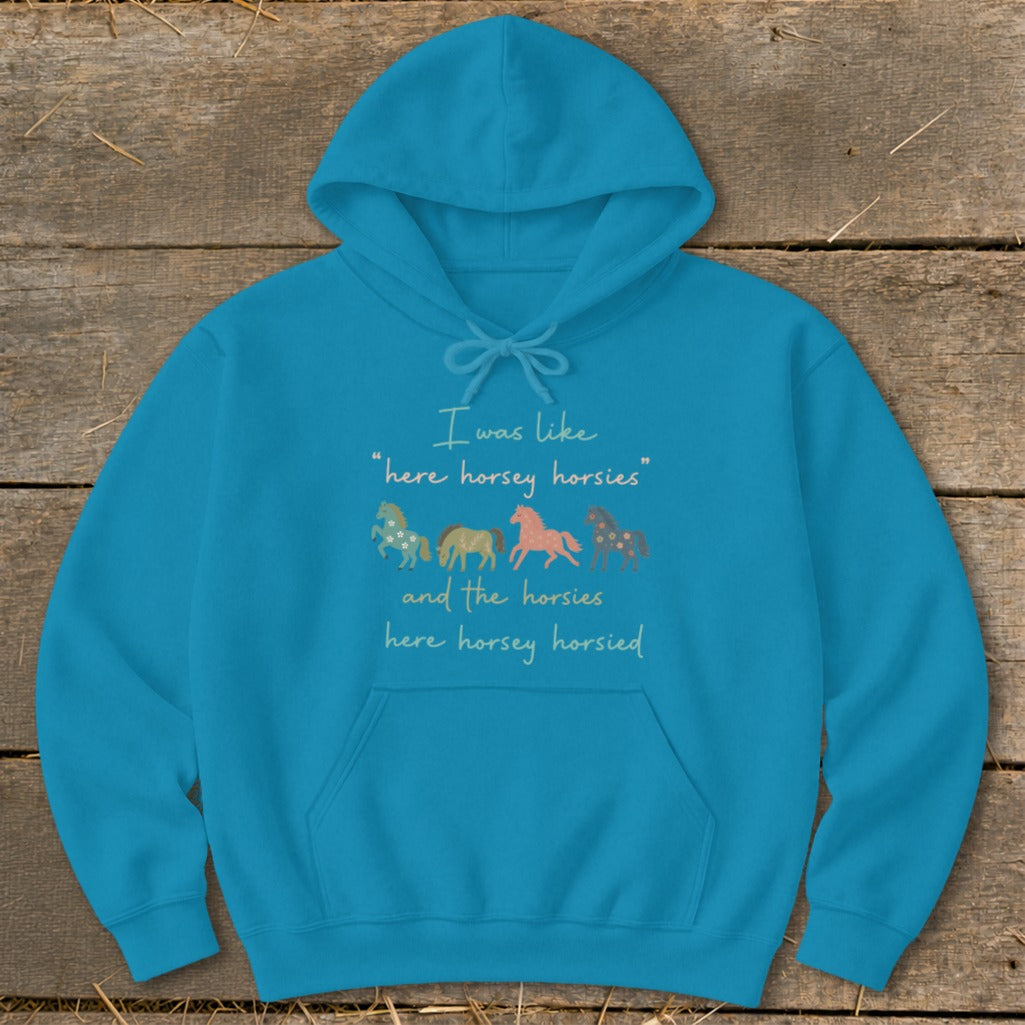 Teal hoodie with text and four illustrated horses in pastel colors.