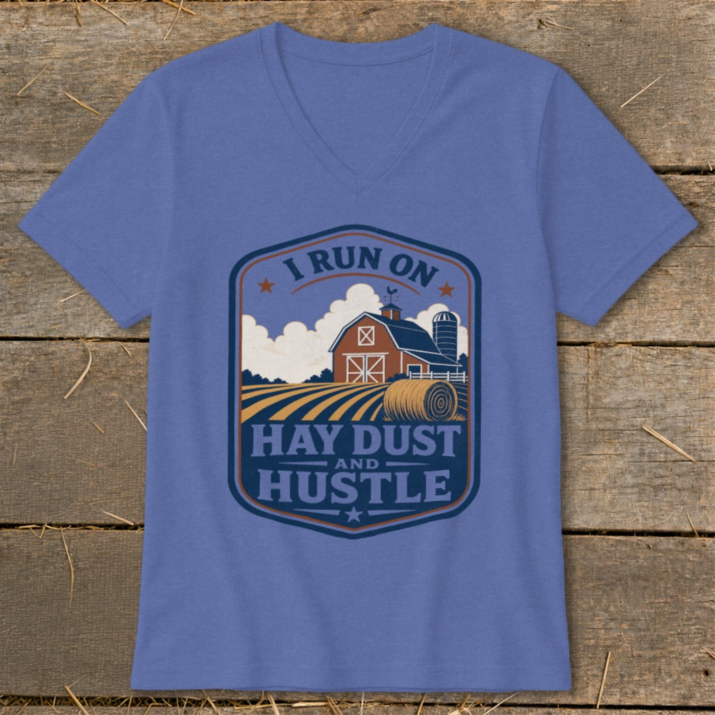 Blue v-neck t-shirt with a rustic farm scene graphic that reads "I run on hay dust and hustle."