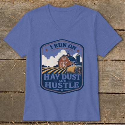 Blue v-neck t-shirt with a rustic farm scene graphic that reads "I run on hay dust and hustle."