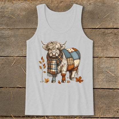 Highland cow with patchwork body and scarf, surrounded by autumn leaves.