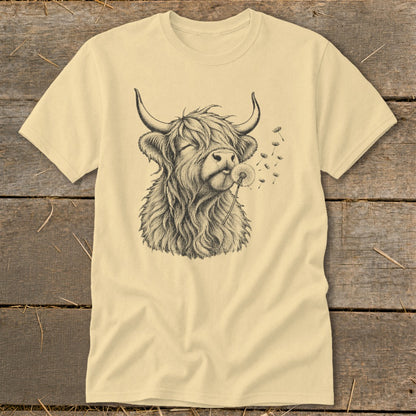 Highland cow blowing a dandelion on a cream t-shirt