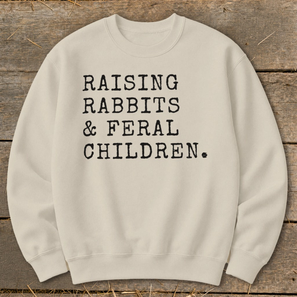 Cream sweatshirt with black text: Raising Rabbits & Feral Children.